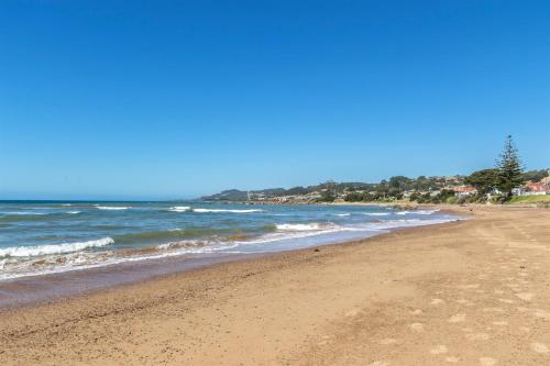 a sandy beach with the ocean on a sunny day at Madsen Retreat in Penguin