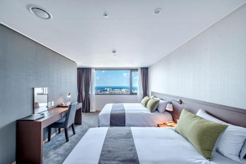 ein Hotelzimmer mit 2 Betten und einem Schreibtisch in der Unterkunft Hotel Shalom Jeju in Jeju-do