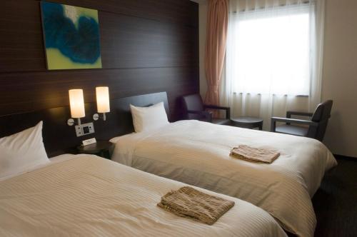 ein Hotelzimmer mit 2 Betten und einem Fenster in der Unterkunft Route Inn Grantia Shiretoko Shari Ekimae in Shari