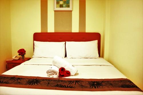 a bed with a towel and a red flower on it at Sun Inns Hotel Equine, Seri Kembangan in Seri Kembangan