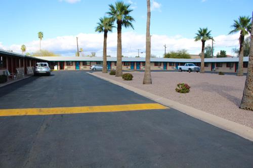 an empty parking lot with palm trees and a building at Starlite Motel in Mesa