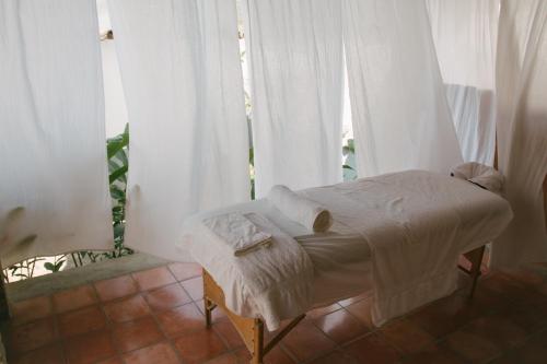 Cama pequeña en habitación con cortinas blancas en Casa Jaguar, en Copan Ruinas