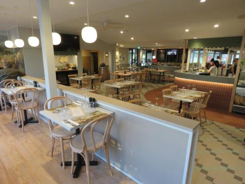 a restaurant with tables and chairs and a bar at Baileys Parkside Motel by VetroBlu in Perth