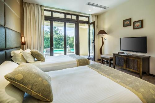 a hotel room with two beds and a flat screen tv at Sanya Yalong Bay Villas & Spa in Sanya