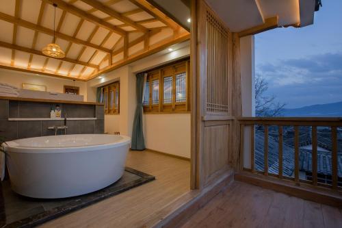 a bath tub in a bathroom with a balcony at Jianshe Inn in Lijiang