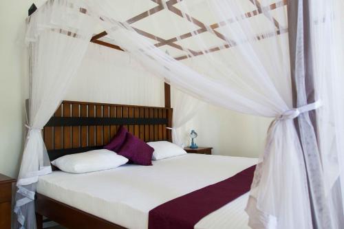 a bedroom with a bed with a canopy at Villa Olga in Unawatuna