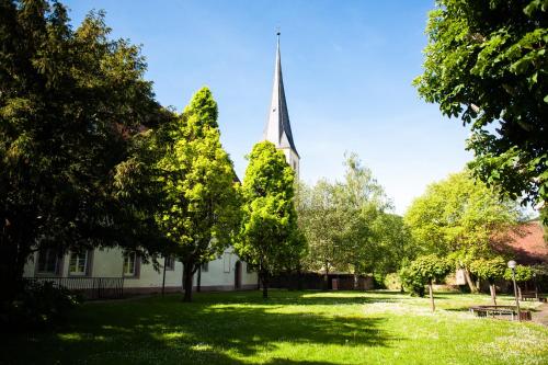 a church with a spire in the middle of a yard at Bildungshaus Neckarelz in Mosbach