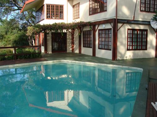 uma piscina em frente a uma casa em Kayube Zambezi River House em Livingstone