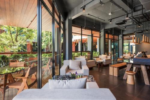 a lobby with tables and chairs and glass windows at The Habita Hatyai in Hat Yai