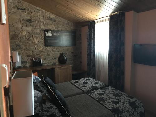 a bedroom with a bed and a stone wall at Santa Bárbara in Sant Corneli de Cercs 