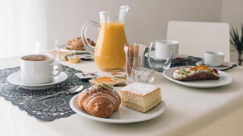 a table topped with plates of breakfast foods and orange juice at Alludo Aparthotel b&b in Agrigento