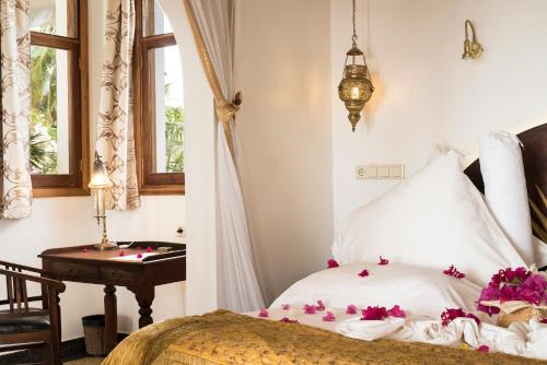 a bedroom with a bed and a desk and a window at Boutique Hotel Matlai in Michamvi