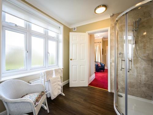 a bathroom with a shower and a chair and a glass door at Barnard House in Great Yarmouth