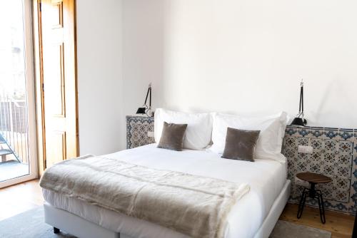 a bedroom with a large white bed with pillows at Flora Chiado Apartments in Lisbon