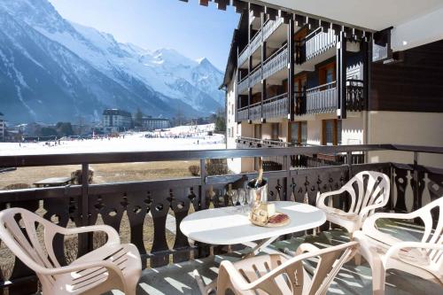 a white table and chairs on a balcony with mountains at Les Balcons du Savoy 104 appt - Chamonix All Year in Chamonix