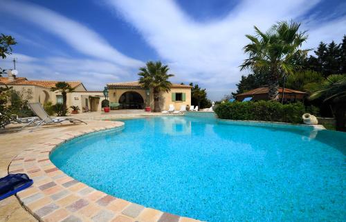 una gran piscina de agua azul en un patio en Mas de la Montille, en Aigues-Mortes