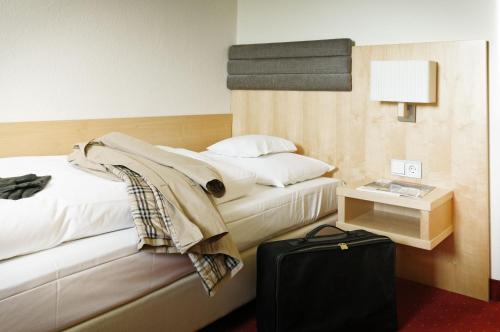 a hotel room with a bed and a table with a suitcase at Hotel de France Wiesbaden City in Wiesbaden