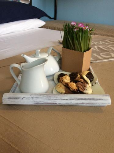 a plate of cookies and a pot of flowers on a table at Sweet Home & Apartments in Fontane Bianche