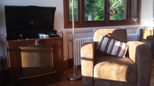 uma sala de estar com uma cadeira e uma televisão em 13 Bees em Confolens
