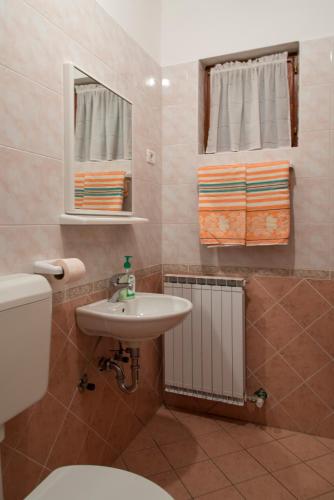 a bathroom with a sink and a toilet and a mirror at Apartmaji Tim in Izola