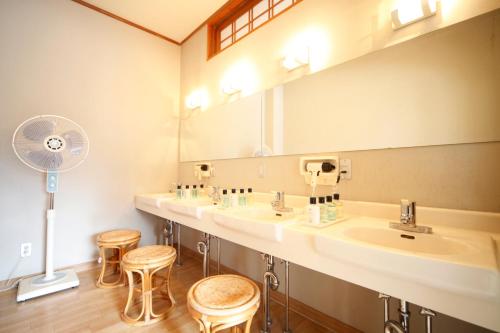 a bathroom with three sinks and a fan and stools at Oribana in Omachi