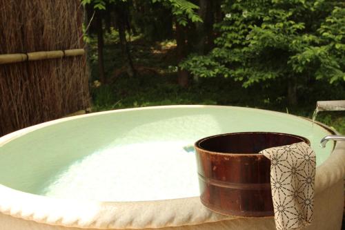 a bath tub with a bucket in the middle at Oribana in Omachi