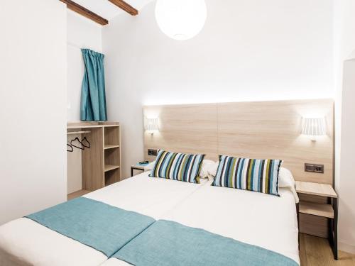 - une chambre avec un lit blanc et une tête de lit en bois dans l'établissement UNIK. Apartments Valencia, à Valence