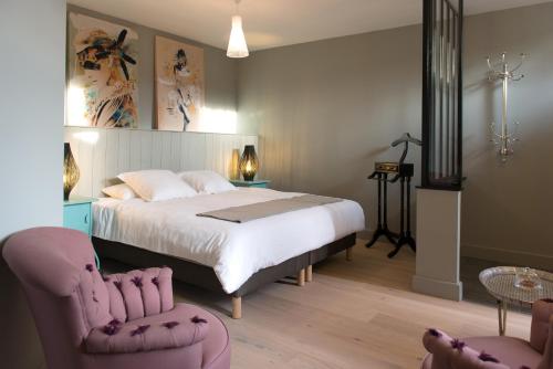 a bedroom with a large bed and two chairs at Plumes & Coton in Écurie