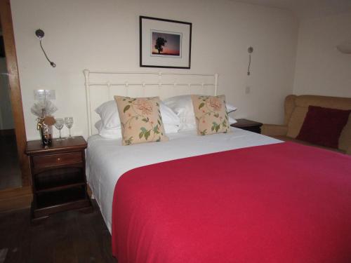 a bedroom with a large bed with a red blanket at The Kilcot Inn in Newent