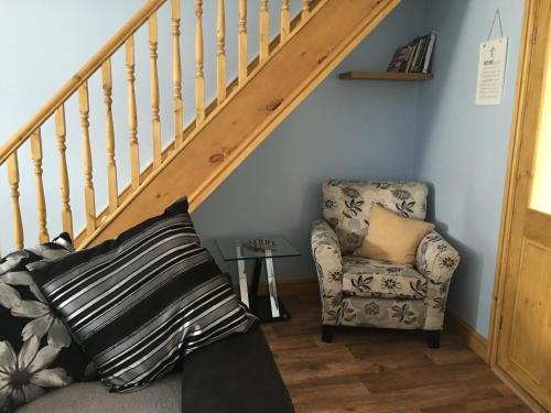 a stair room with a chair and a stair case at Waters Edge in Penclawdd