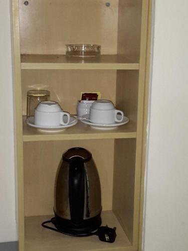 a wooden cupboard with a tea kettle and dishes at Tanjung Demong Beach Resort in Kuala Besut