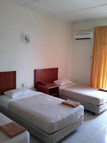 a hotel room with two beds and a window at Tanjung Demong Beach Resort in Kuala Besut