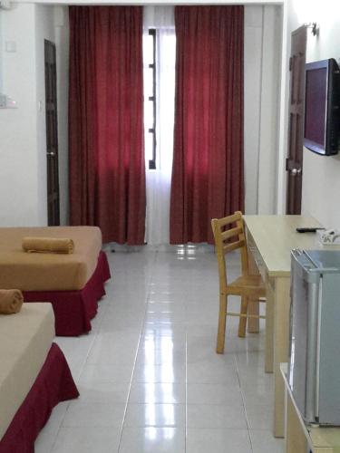 a room with two beds and a table and a television at Tanjung Demong Beach Resort in Kuala Besut