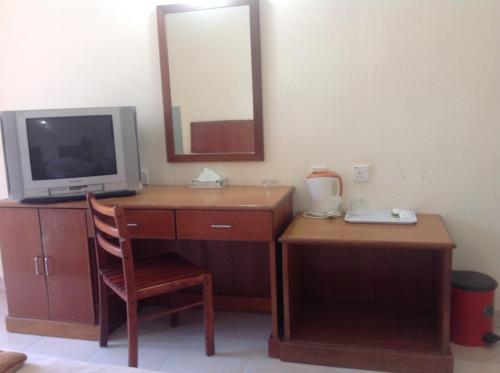 a room with a desk with a television and a mirror at Tanjung Demong Beach Resort in Kuala Besut