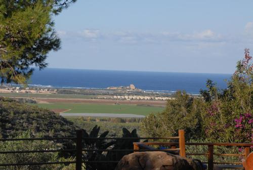 a view of the ocean from a hill with a fence at Above the Sea in ‘En Hod