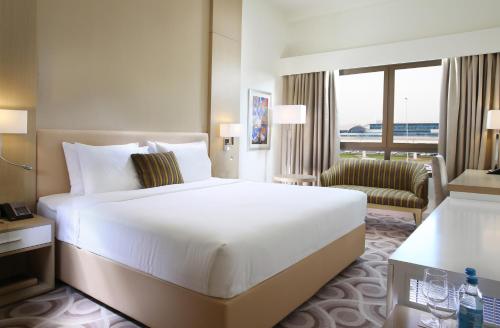 a hotel room with a large white bed and a chair at Metropolitan Hotel Dubai in Dubai