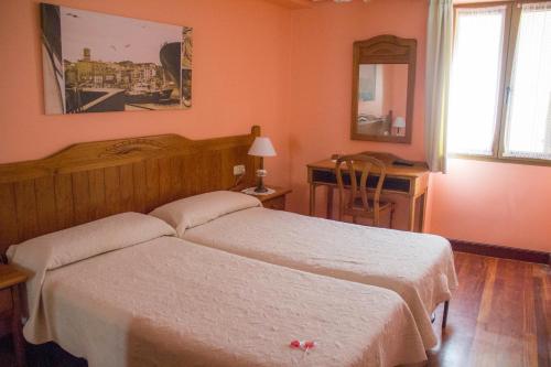 a bedroom with two beds and a desk with a mirror at Pension Getariano in Getaria