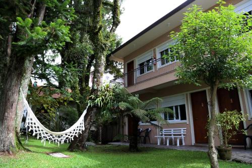a hammock hanging from trees in front of a house at Pousada Caminho das Rosas-Gramado-temporada ou diária in Gramado