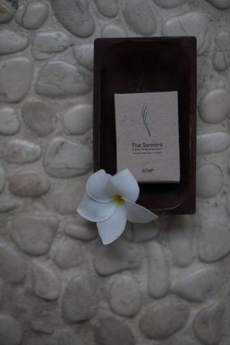 a white flower on a stone wall with a card at The Samara Villas & Restaurant in Ubud
