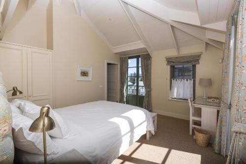 a bedroom with a white bed and a window at The Majestic Apartments in Kalk Bay