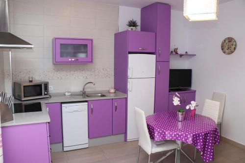 コニル・デ・ラ・フロンテーラにあるApartamento céntricoのキッチン(紫色のキャビネット、紫色のテーブルクロス付きのテーブル付)