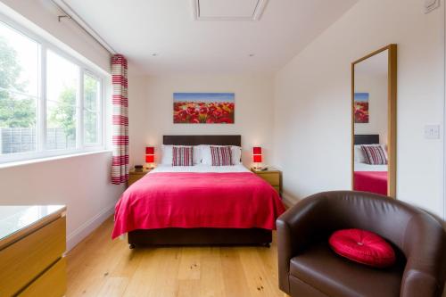 a bedroom with a red bed and a chair at 1 Suffolk Cottage in Aldeburgh