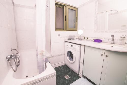 a white bathroom with a washing machine and a sink at Nefeli City Apartments in Patra