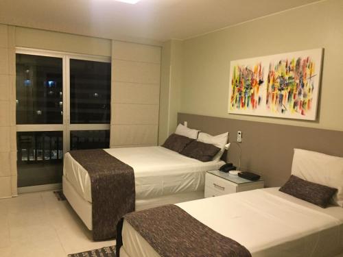 a hotel room with two beds and a window at Flat Fusion Setor Hoteleiro Norte com serviço diário de limpeza in Brasilia