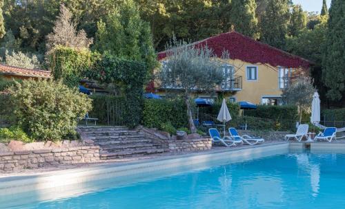 a swimming pool with chairs and a house at Tenuta La Bandita in Sassetta