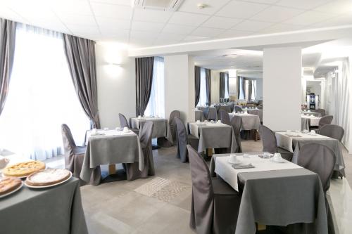 un ristorante con tavoli e sedie grigi e cercapersone di Hotel Principe a Modena