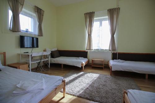 a room with two beds and a table and a tv at Gyevitur Apartman in Algyő