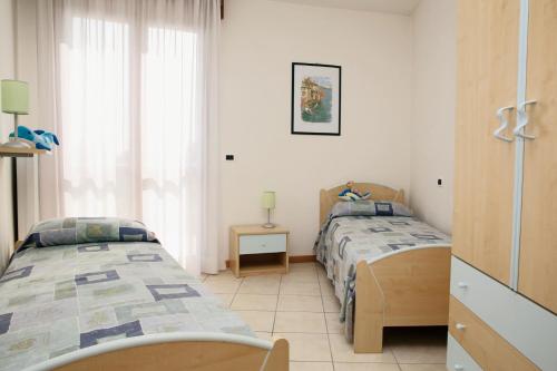 two twin beds in a room with a window at Appartamenti Joker Vallenova in Cavallino-Treporti