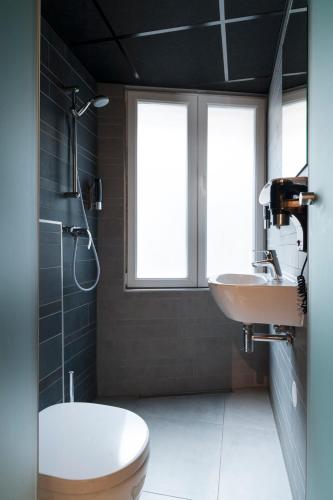 a bathroom with a sink and a toilet and two windows at Urban City Centre Hostel in Brussels