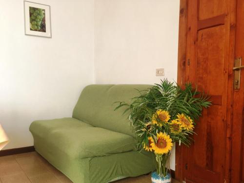 a green couch in a room with a vase of flowers at Camping Hotel Au Lac De Como in Sorico